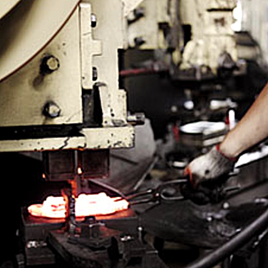 Hot forging press striking a glowing billet